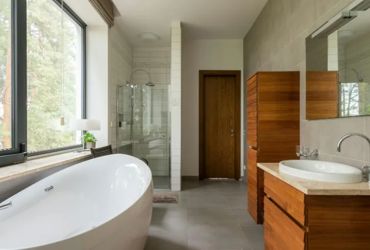 Baño amplio de chalet con bañera exenta junto al ventanal y mueble de lavabo de madera