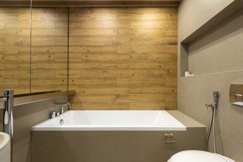 Baño con bañera y revestimiento de madera en Zaragoza
