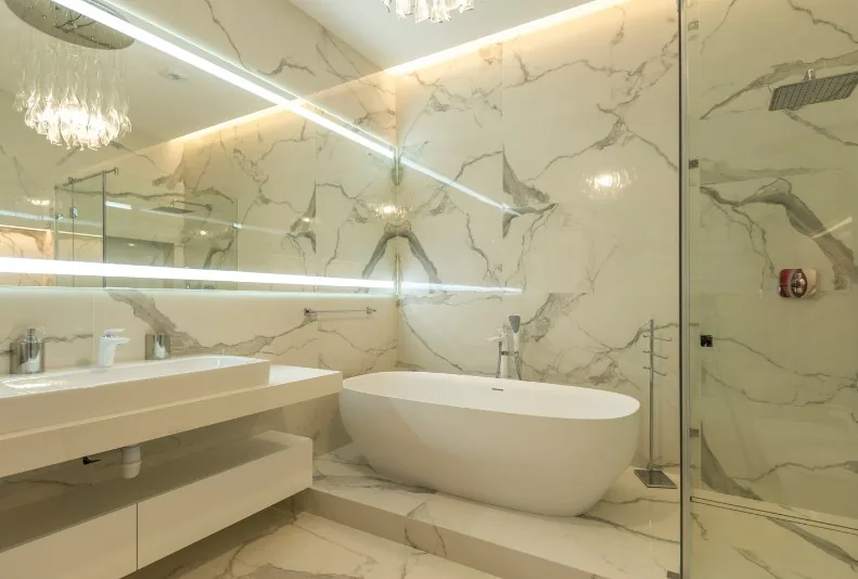 Baño de lujo con porcelánico efecto mármol a toda altura, bañera exenta y ducha acristalada en el Centro de Zaragoza