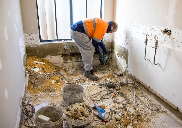 Vaciado de un baño con tuberías al descubierto y retirada de escombros